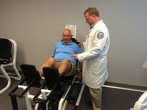 Dr. Richard Dennis is shown leading a Veteran through leg exercises for a study at the Little Rock VAMC funded by the Rehabilitation R&D Merit program.  The study is a double blind trial testing the effects of a nutritional supplement on improving muscle mass, strength, and function in older adults.